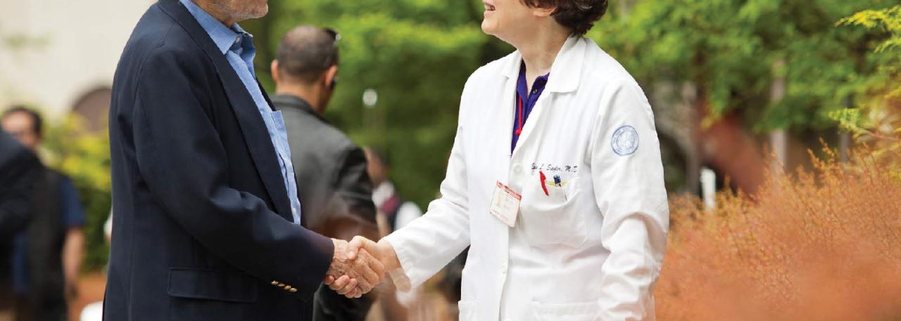 An older adult shakes hands with a geriatrician outside of the hospital.