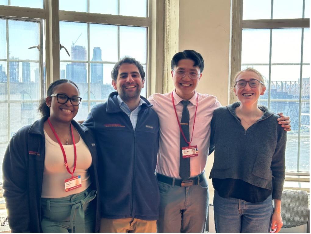 the community outreach team poses in front of windows overlooking NYC skyline